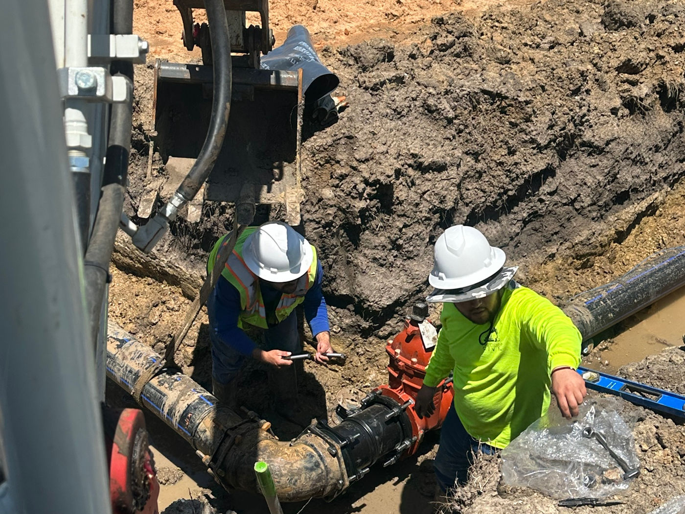Crew working on pipe connection in excavation
