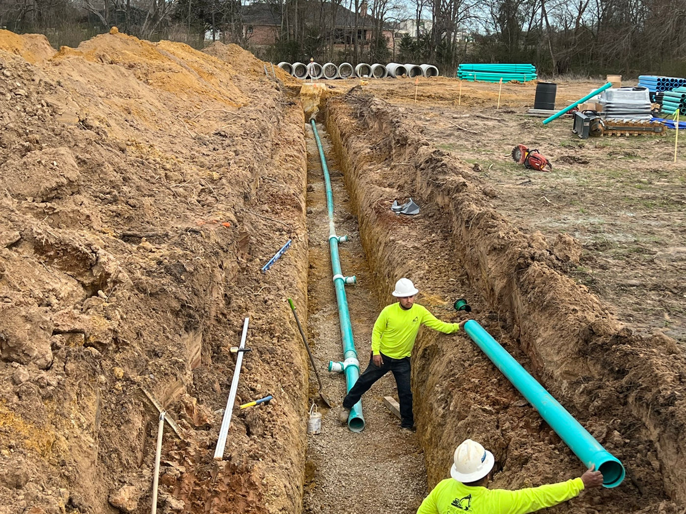 Crew member handling utility pipe in trench